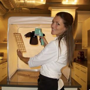 Chef spraying chocolate in a controlled spray tent